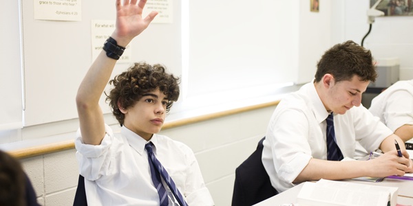 boy with raised hand in classromm