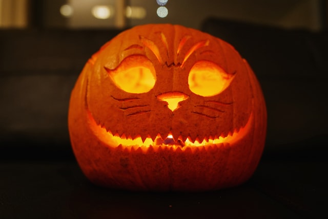 carved halloween pumpkin lit up from within, smiling, also with nose and eyes