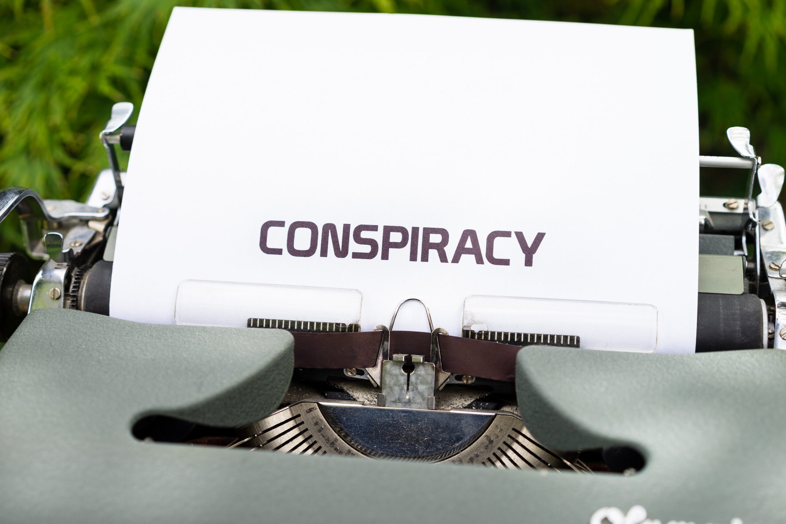 image of manual typewriter with sheet of white paper in carriage saying CONSPIRACY